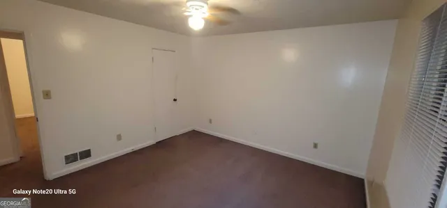 an empty room with a ceiling fan and window