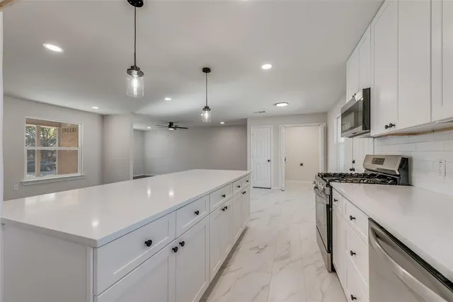 a large kitchen with stainless steel appliances granite countertop a sink a stove and a refrigerator