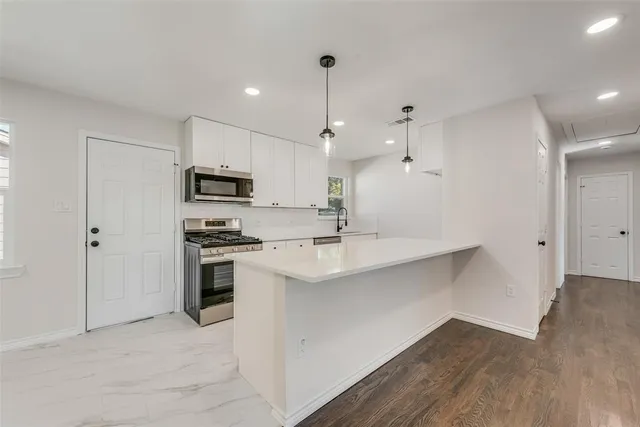 a kitchen with stainless steel appliances a sink a stove a refrigerator and cabinets