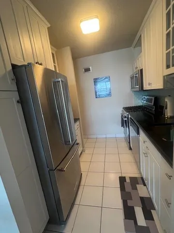 a kitchen with granite countertop stainless steel appliances a sink a stove a refrigerator a microwave oven and white cabinets