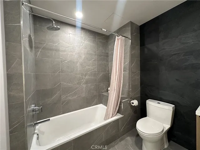 a white toilet sitting next to a bath tub and a shower