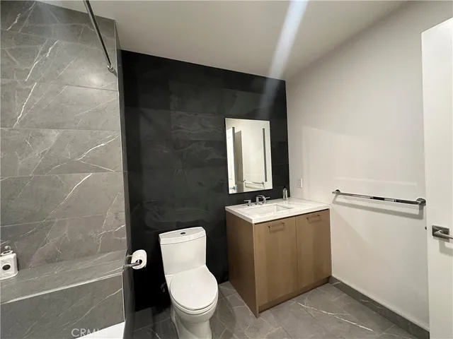 a bathroom with a granite countertop toilet sink and mirror