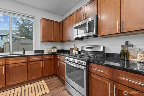 a kitchen with stainless steel appliances granite countertop a stove a sink and a microwave