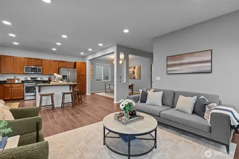 a living room with furniture kitchen view and a wooden floor