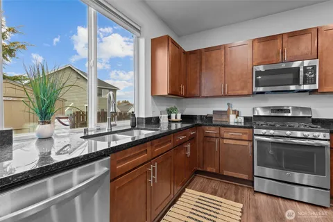 a kitchen with stainless steel appliances granite countertop a sink a stove and cabinets