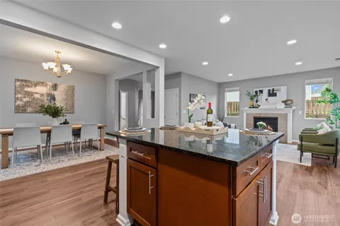 a dining hall with stainless steel appliances granite countertop a table chairs and a refrigerator a sink with wooden floor