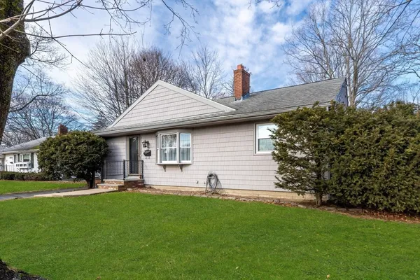 a front view of a house with a yard and trees