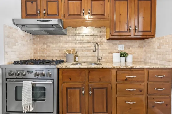 a kitchen with granite countertop a stove sink and cabinets