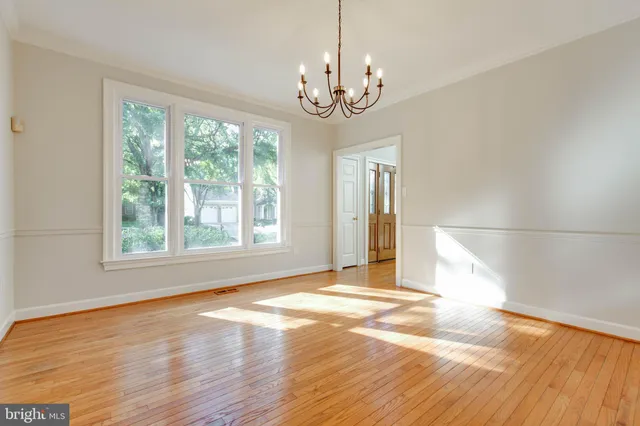 an empty room with wooden floor fireplace and windows