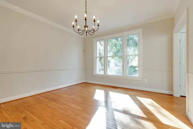 an empty room with wooden floor fireplace and windows