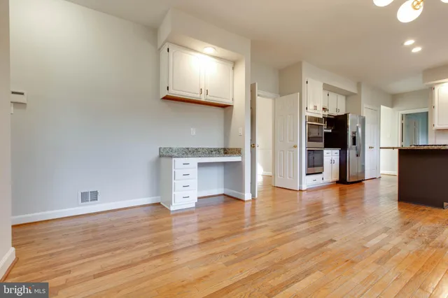 a kitchen with stainless steel appliances granite countertop a stove top oven a sink dishwasher a refrigerator and white cabinets with wooden floor