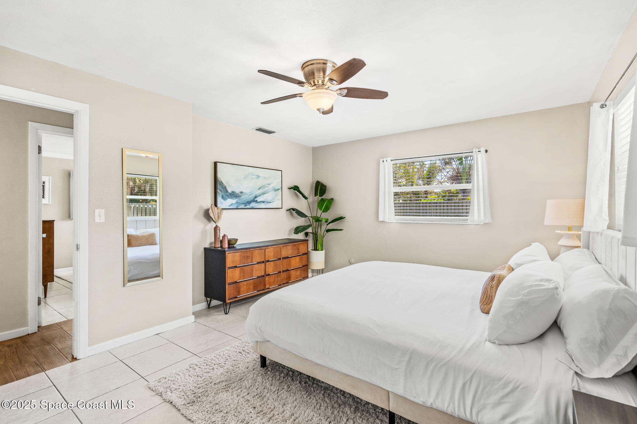 411 Poinsettia Road Melbourne Beach, FL 32951 - Photo 16 of 78 a bedroom with a large bed and a chandelier
