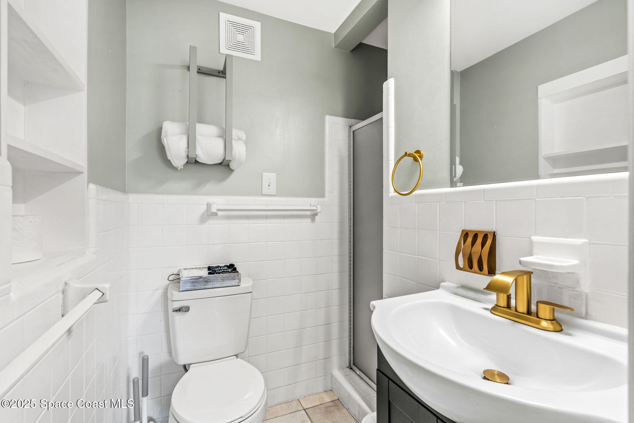 411 Poinsettia Road Melbourne Beach, FL 32951 - Photo 18 of 78 a bathroom with a sink a toilet and mirror