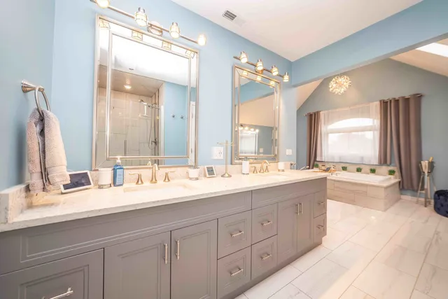 a bathroom with a granite countertop double vanity sink a mirror and a bathtub