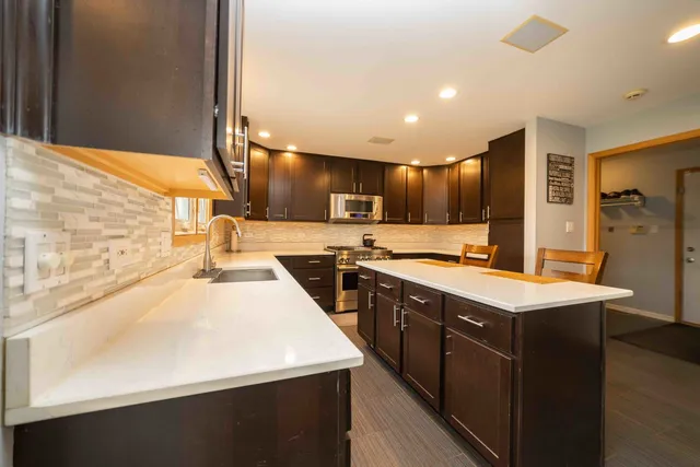 a kitchen with stainless steel appliances granite countertop a sink a stove and a refrigerator