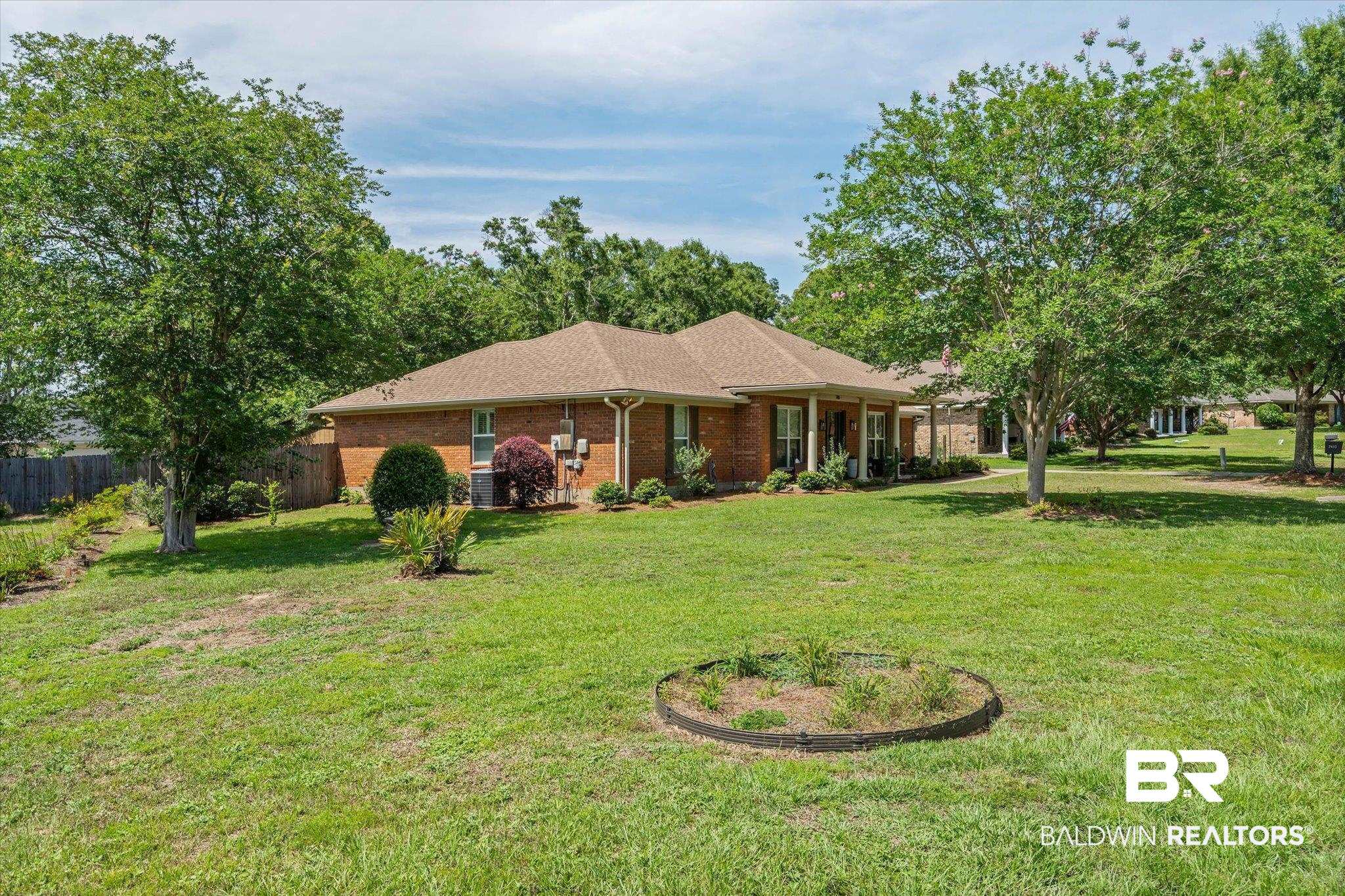 7410 Smithfield Road East Mobile, AL 36695 - Photo 22 of 24 Expansive lawn surrounding a brick residence with a hip roof, mature trees, and a shaded front porch
