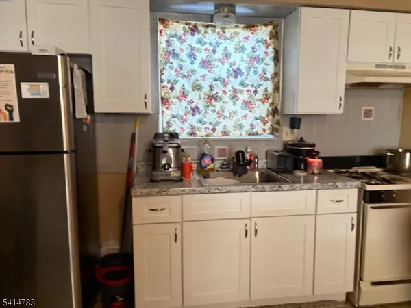 a kitchen with stainless steel appliances granite countertop a refrigerator sink and white cabinets