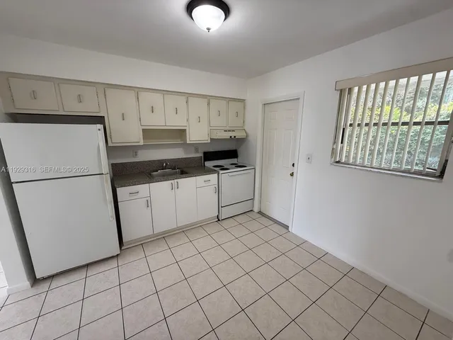 a kitchen with white cabinets a refrigerator and a sink
