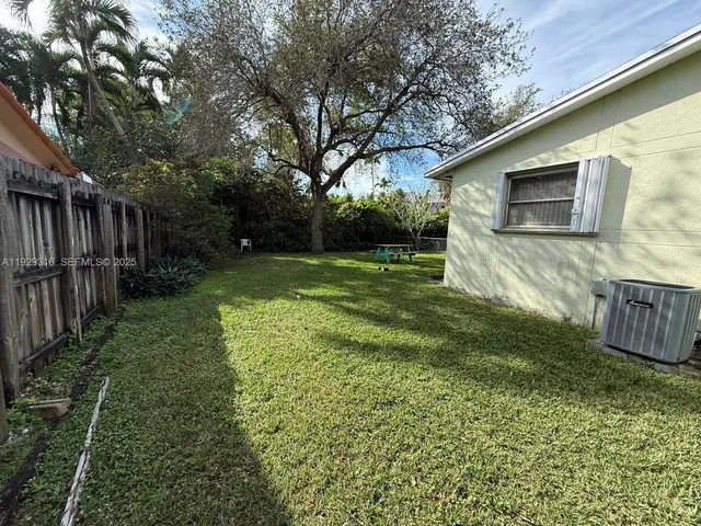 a view of a backyard with large trees and wooden fence