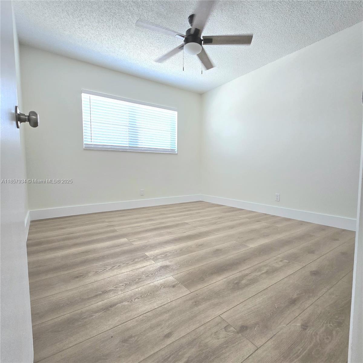 5300 Washington Street, Unit I205 Hollywood, FL 33021 - Photo 10 of 20 an empty room with wooden floor ceiling fan and windows