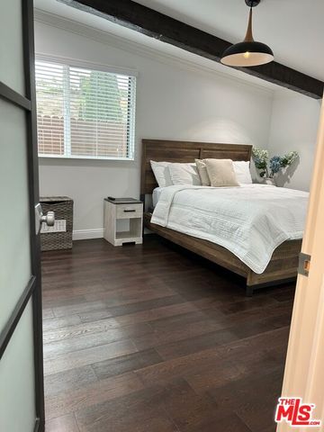 a bedroom with a bed and a potted plant on the dresser