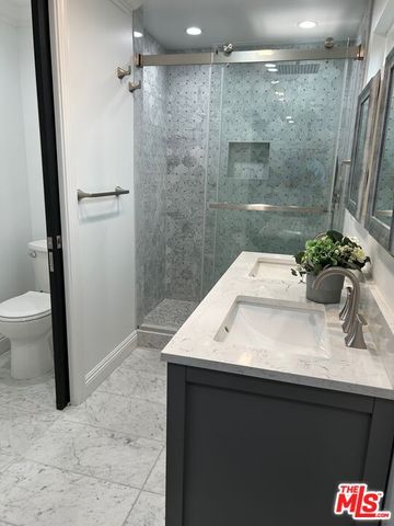 a bathroom with a granite countertop sink a mirror and a shower