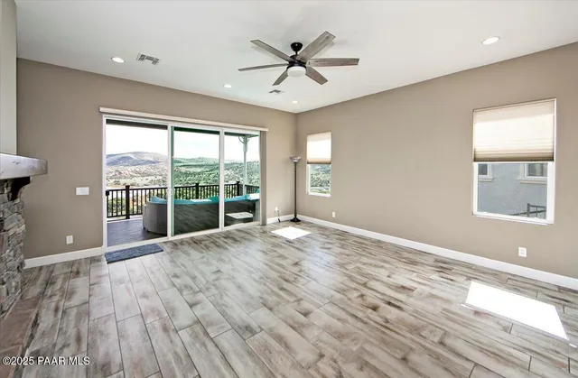 a view of an empty room with a window and wooden floor