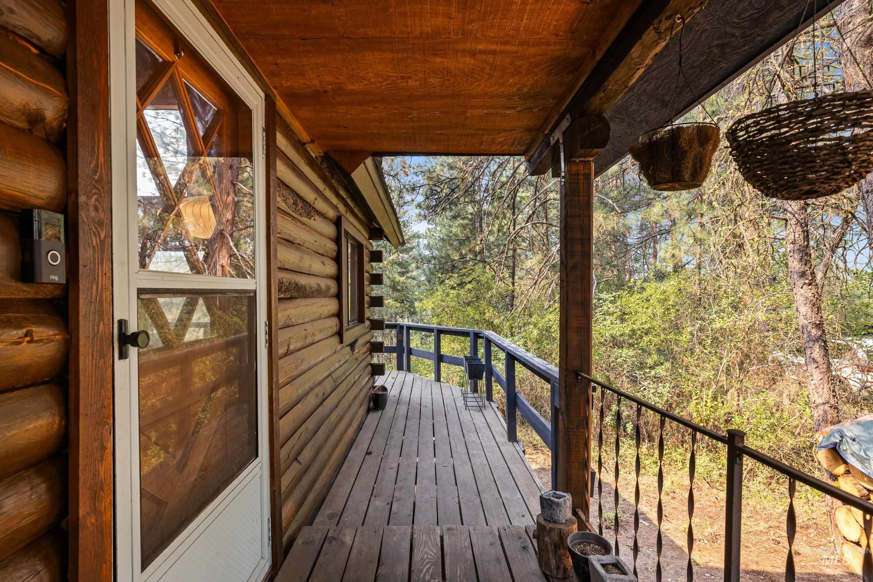 73 Rainbow Ridge Road Garden Valley, ID 83622 - Photo 5 of 49 Wood-log exterior construction featuring a covered wood-plank deck with a decorative iron railing