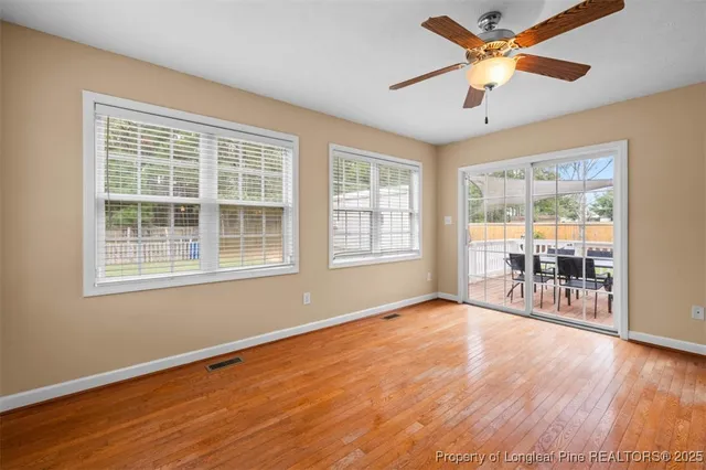 a view of an empty room with a window and wooden floor