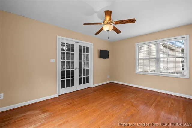 a view of an empty room with a window and wooden floor
