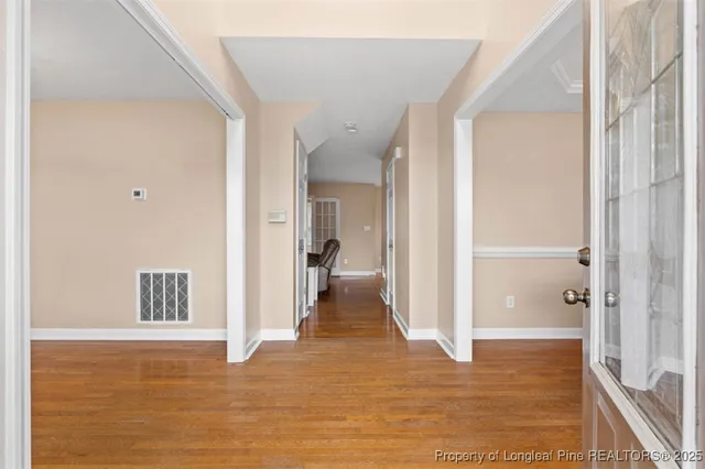 a view of a hallway with wooden floor and a bathroom