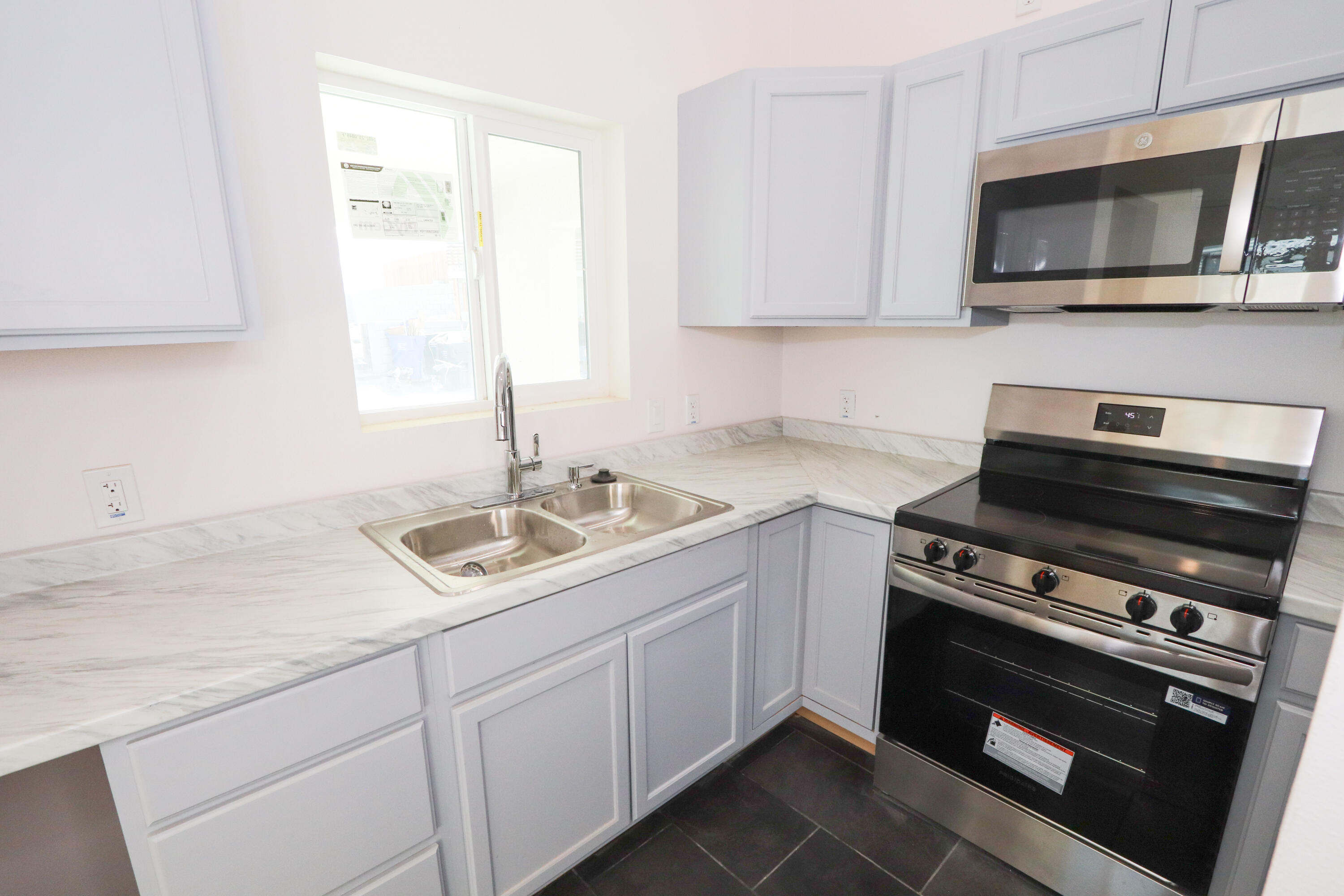 10900 Telimo Way, Unit B Desert Hot Springs, CA 92240 - Photo 8 of 10 a kitchen with stainless steel appliances granite countertop a sink dishwasher a stove and a microwave oven with cabinets