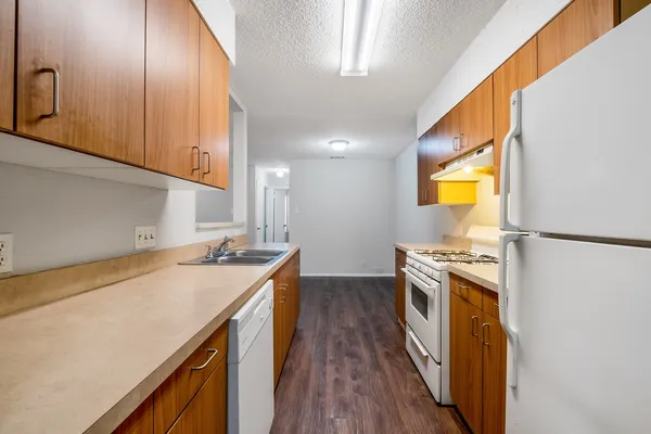 a kitchen with a sink a stove top oven and wooden floor