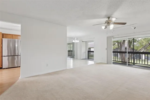 a view of an empty room with chandelier fan