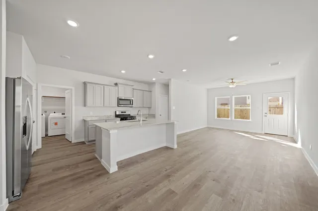 a large white kitchen with stainless steel appliances granite countertop a large counter top and a wooden floors