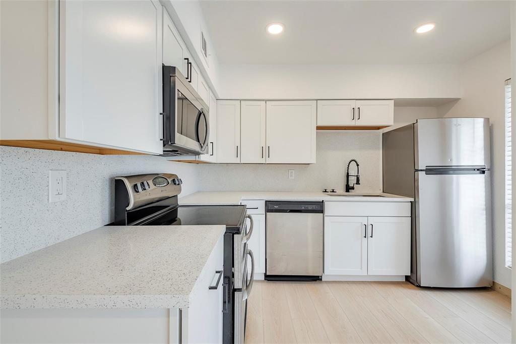 4664 Matilda Street, Unit F Dallas, TX 75206 - Photo 2 of 13 Kitchen with stainless steel appliances, white cabinetry, decorative backsplash, light wood-type flooring, and light stone countertops
