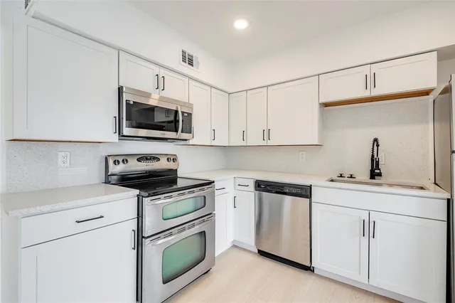 a kitchen with granite countertop white cabinets and stainless steel appliances