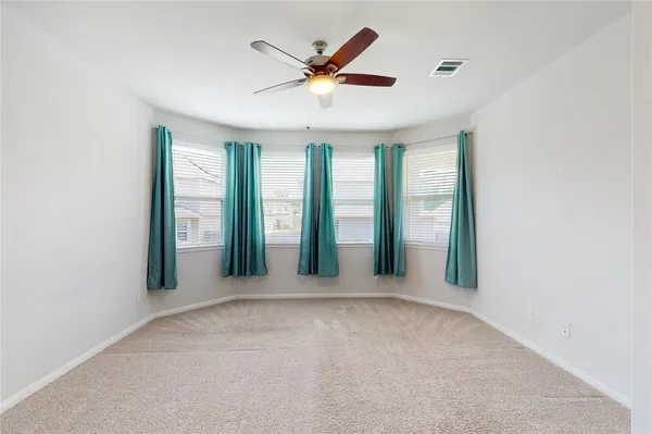 an empty room with windows and ceiling fan