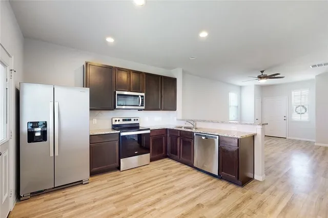 a kitchen with stainless steel appliances granite countertop a stove refrigerator sink and microwave