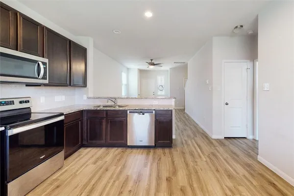 a large kitchen with stainless steel appliances granite countertop a stove a sink and a microwave