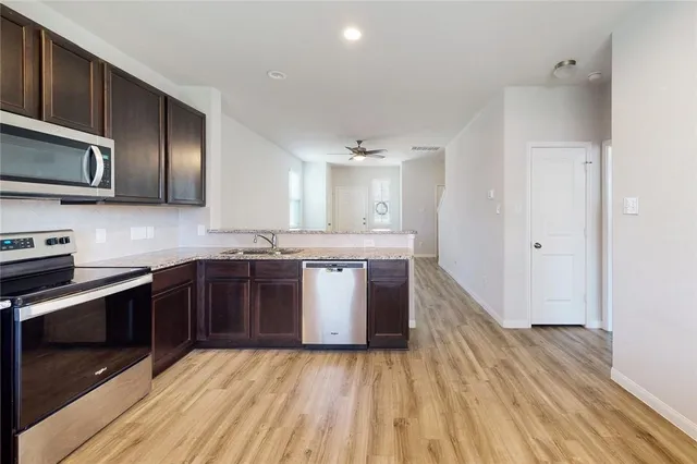 a large kitchen with stainless steel appliances granite countertop a stove a sink and a microwave