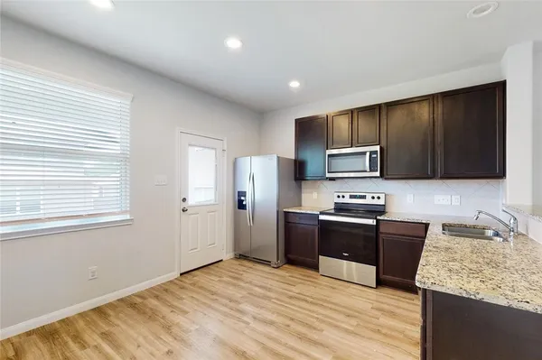 a kitchen with stainless steel appliances granite countertop a sink stove microwave and refrigerator