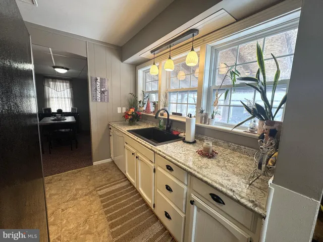 a large white kitchen with granite countertop a sink and a counter top space