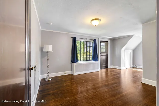 a view of an empty room with window and wooden floor