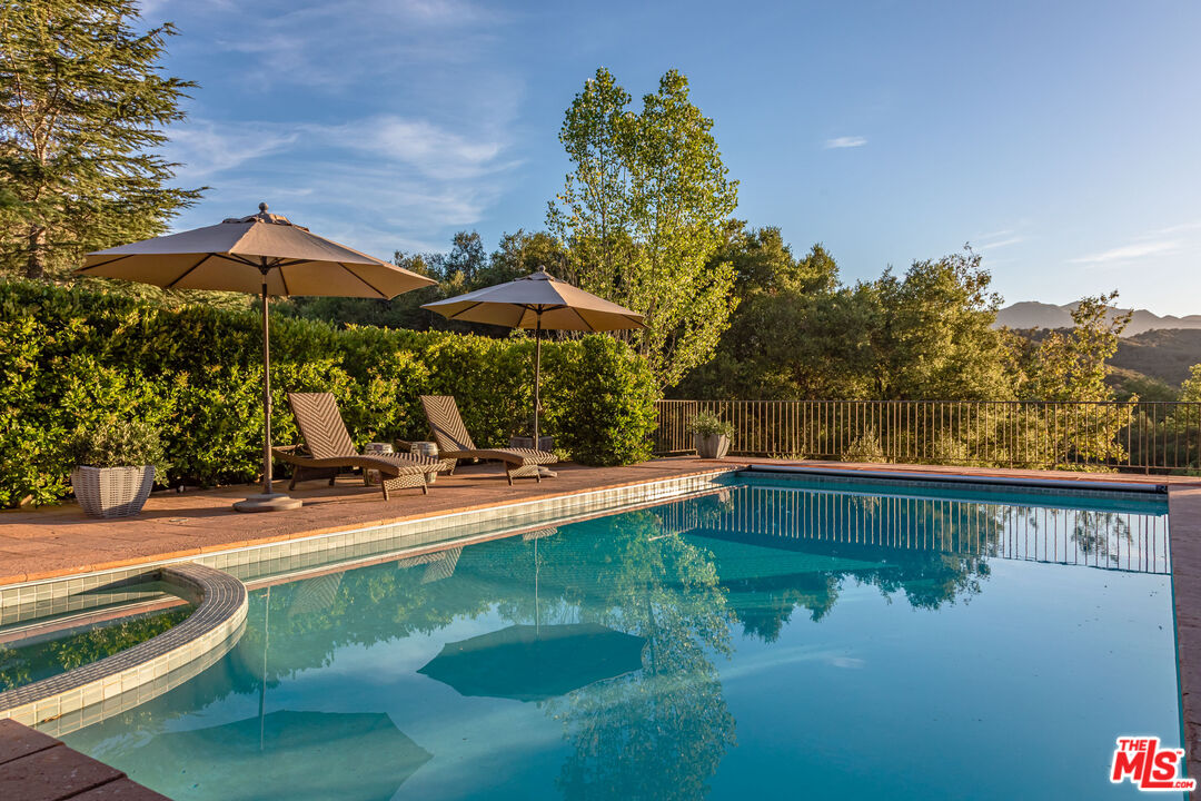 1045 Cold Canyon Road Calabasas, CA 91302 - Photo 47 of 51 a view of swimming pool with a table and chairs under an umbrella