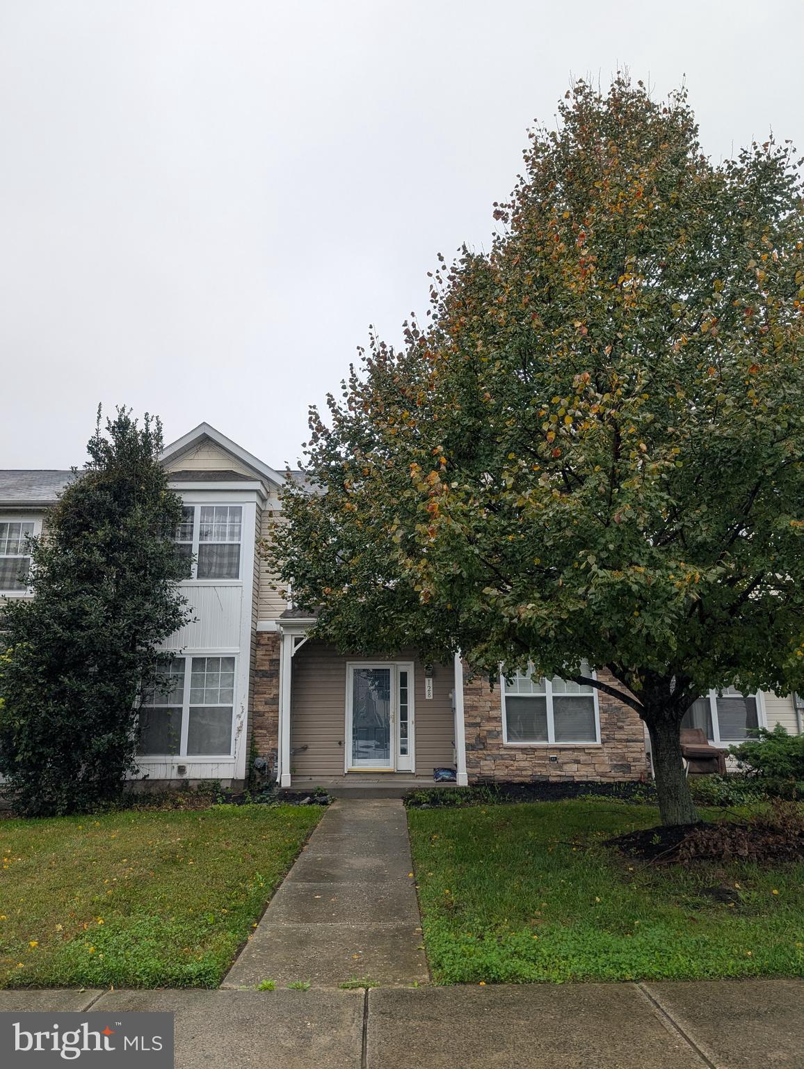 a front view of a house with a garden and trees