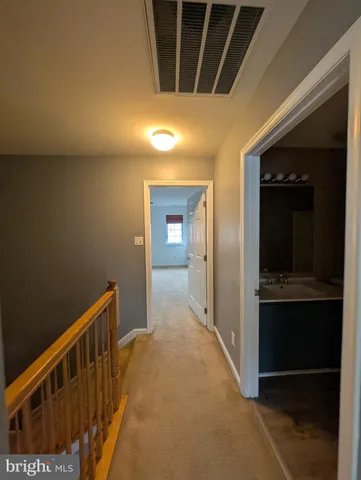 a view of an empty room with wooden floor and stairs