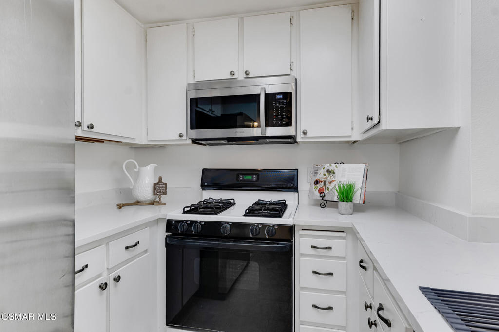 1912 Heywood Street, Unit D Simi Valley, CA 93065 - Photo 6 of 40 a kitchen with stainless steel appliances granite countertop white cabinets and a stove top oven