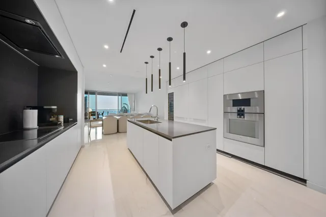 a large white kitchen with a large window a sink and stainless steel appliances