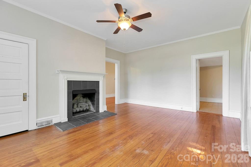 208 West Probart Street Brevard, NC 28712 - Photo 21 of 48 a view of an empty room with wooden floor a fireplace and a window